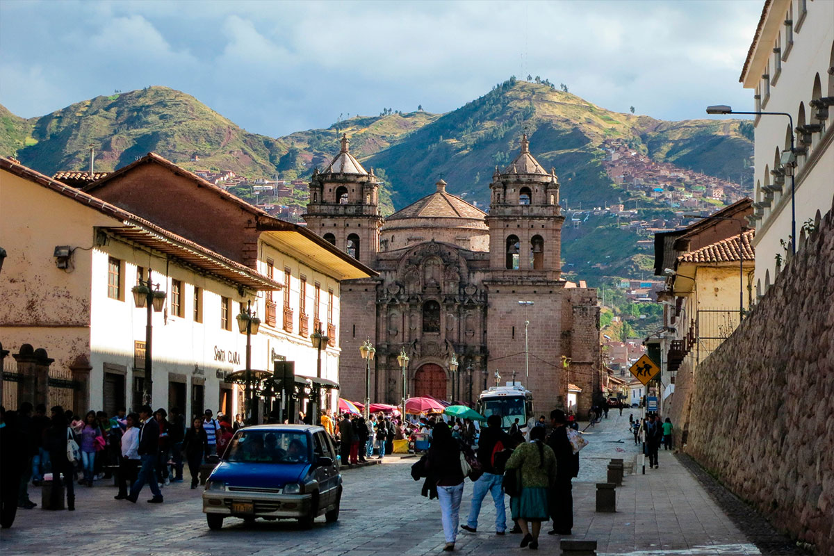 Vibrante escena callejera en el centro de Cusco con personas y automóviles