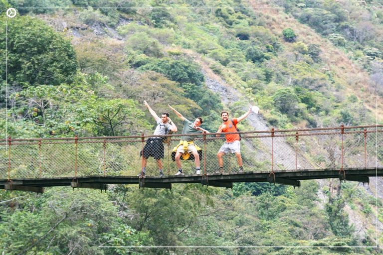 Pura alegría mientras los turistas cruzan un puente que se eleva sobre las aguas salvajes del río por la selva