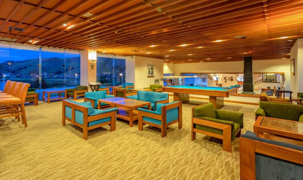 Spacious lounge area at Hotel Libertador Puno with wooden decor, pool table, and panoramic view of Lake Titicaca.
