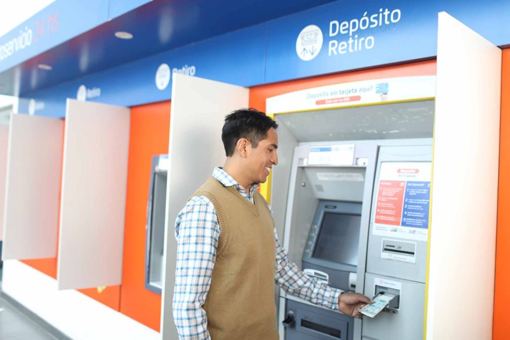 Hombre retirando dinero en efectivo en un cajero automático peruano.