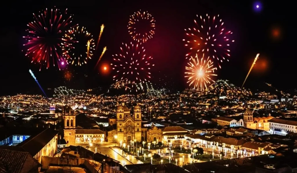 Colorful fireworks lighting up the night sky over Cusco's Plaza de Armas, with historic colonial buildings and city lights during a festive celebration