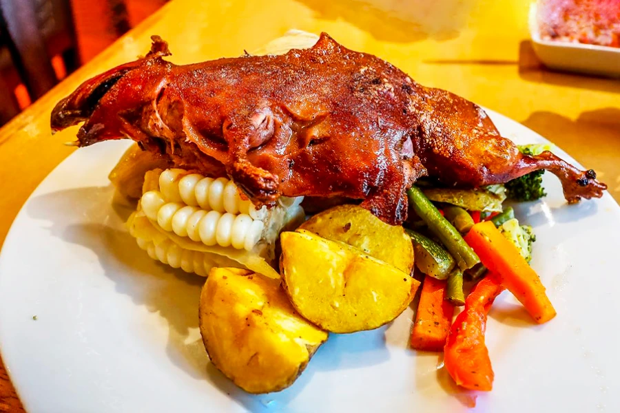 4 platos tradicionales de cuy que debes probar en Perú 2 Cuy al horno, roasted guinea pig served with potatoes and vegetables, a traditional dish from Peru.