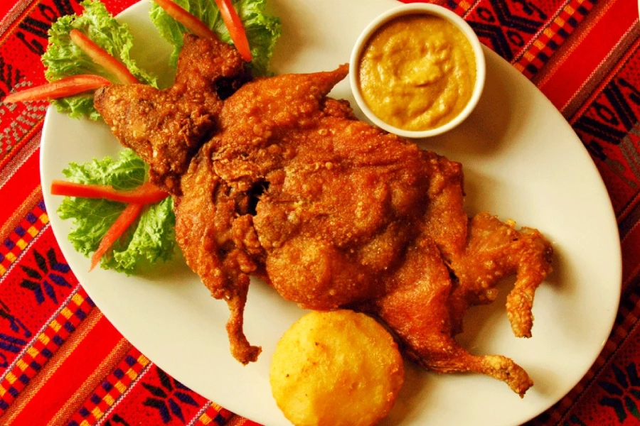 4 platos tradicionales de cuy que debes probar en Perú 3 Crispy cuy chactado, a traditional guinea pig dish from Peru served with potatoes and corn.