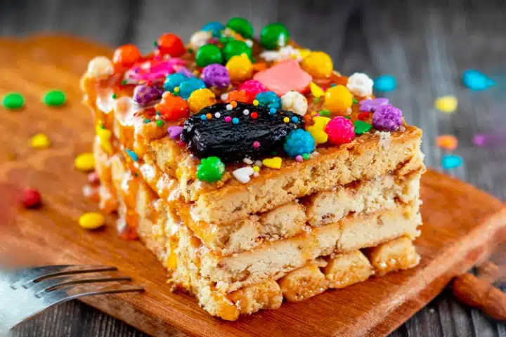 Postres Peruanos Tradicionales que debes probar 6 Traditional Turrón de Doña Pepa dessert decorated with colorful candy sprinkles.
