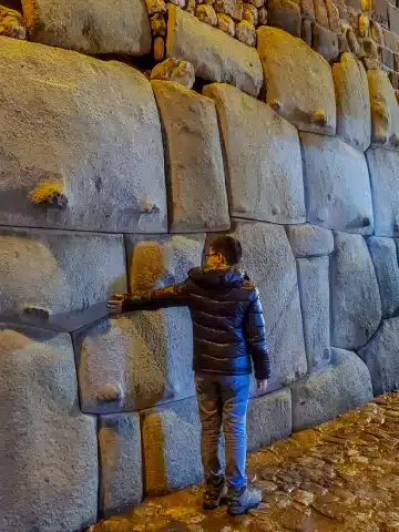 Valle Sagrado vs Cusco: ¿Cuál es mejor para tu viaje a Perú? 3 Visitor standing beside the famous Twelve-Angled Stone, a masterpiece of Inca stonework in Cusco.