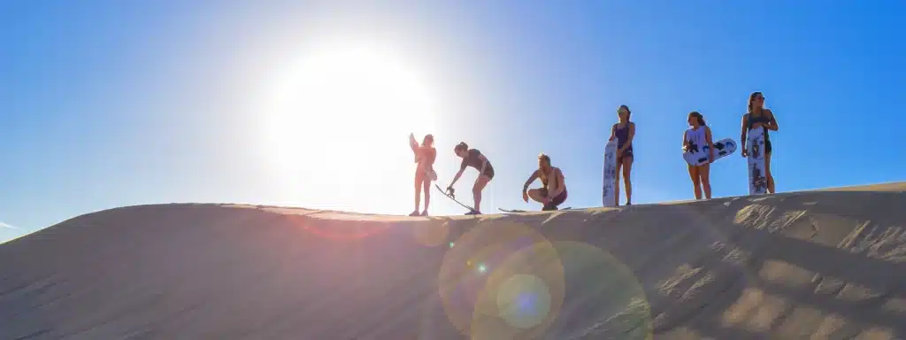 Travelers sandboarding on the Huacachina dunes as part of a Paracas, Ballestas Islands, Huacachina & Nazca itinerary