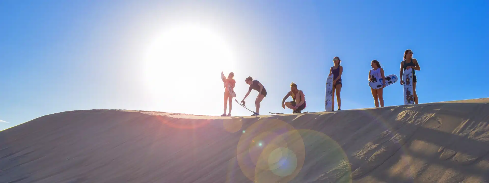 Travelers sandboarding on the Huacachina dunes as part of a Paracas, Ballestas Islands, Huacachina & Nazca itinerary