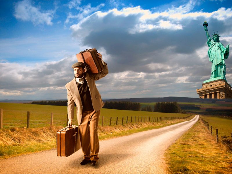 Man with suitcases walking away from the Statue of Liberty in New York, ready to travel to Peru.